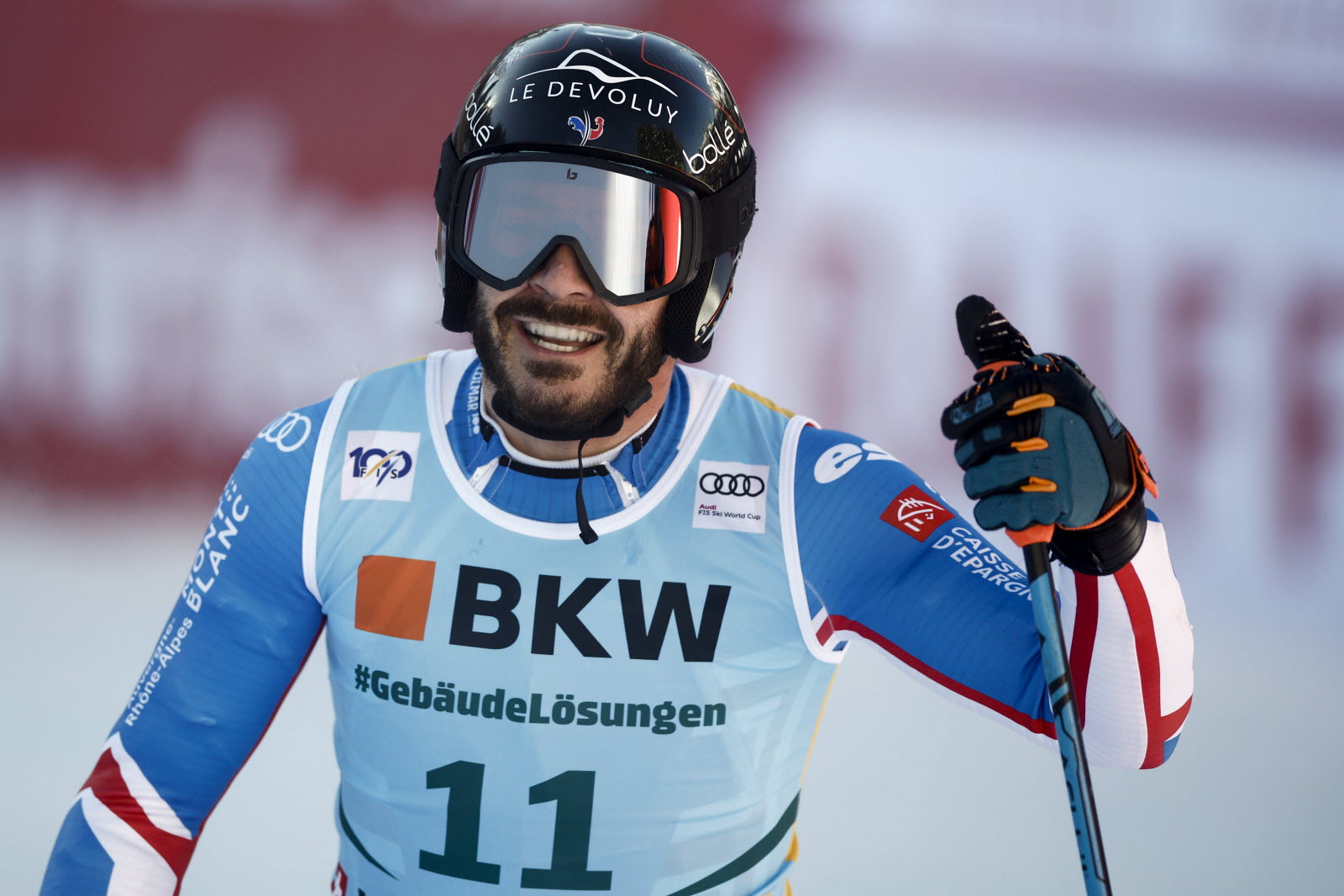 Un portrait de profil d’une femme portant un pull à col roulé ocre et un sac blanc. Elle regarde en l’air et ferme les yeux.